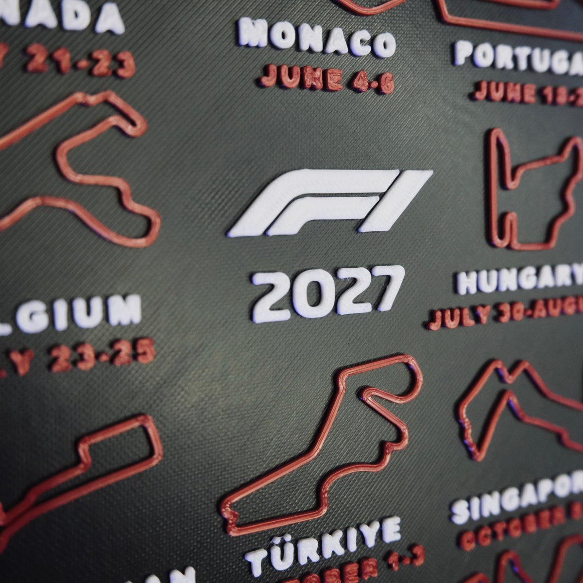 Close-up of the raised 3D printed circuit maps, white country names and red race dates