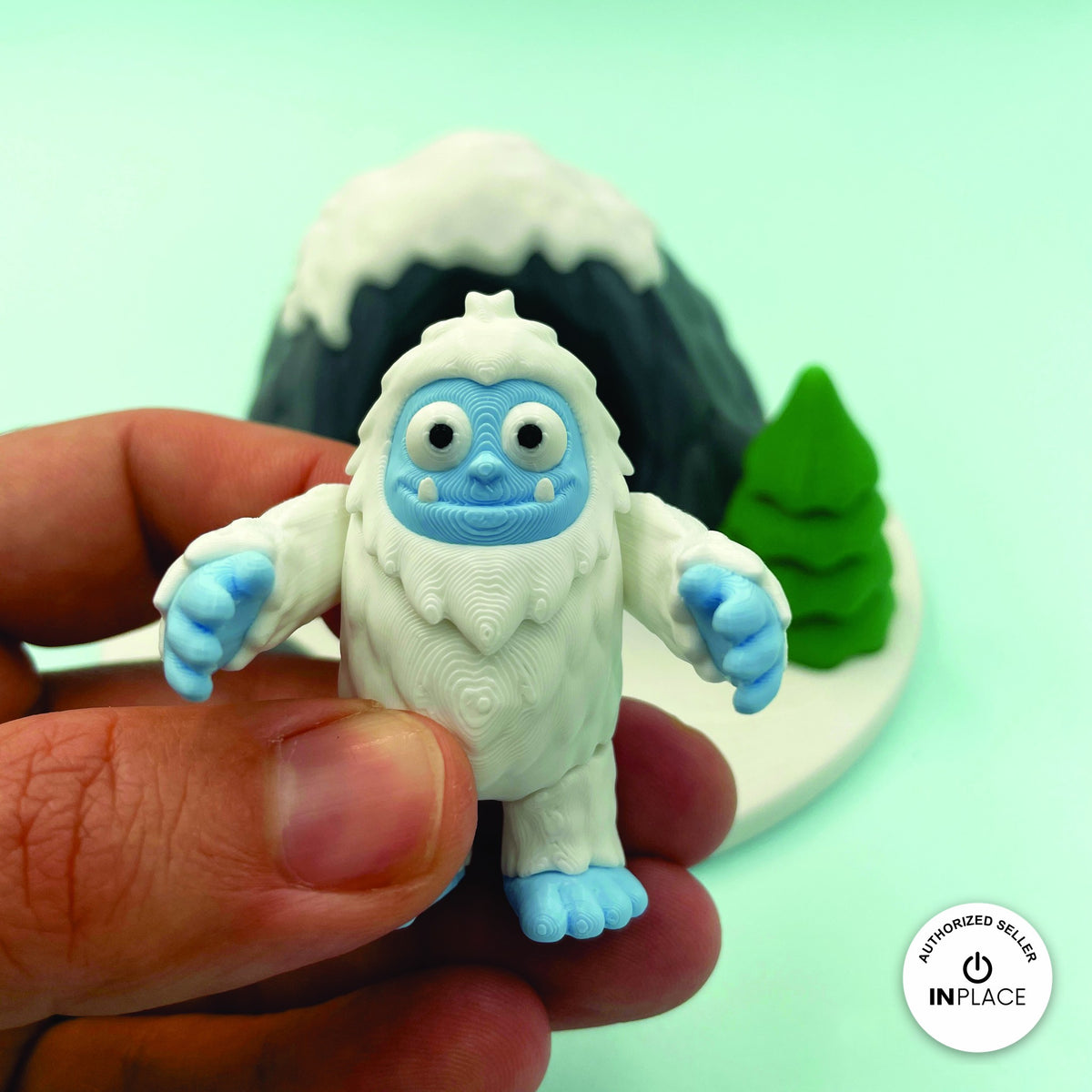 Cute abominable snowman yeti keychain, 3D printed by RU3D – held in hand. White fur with blue face and feet.