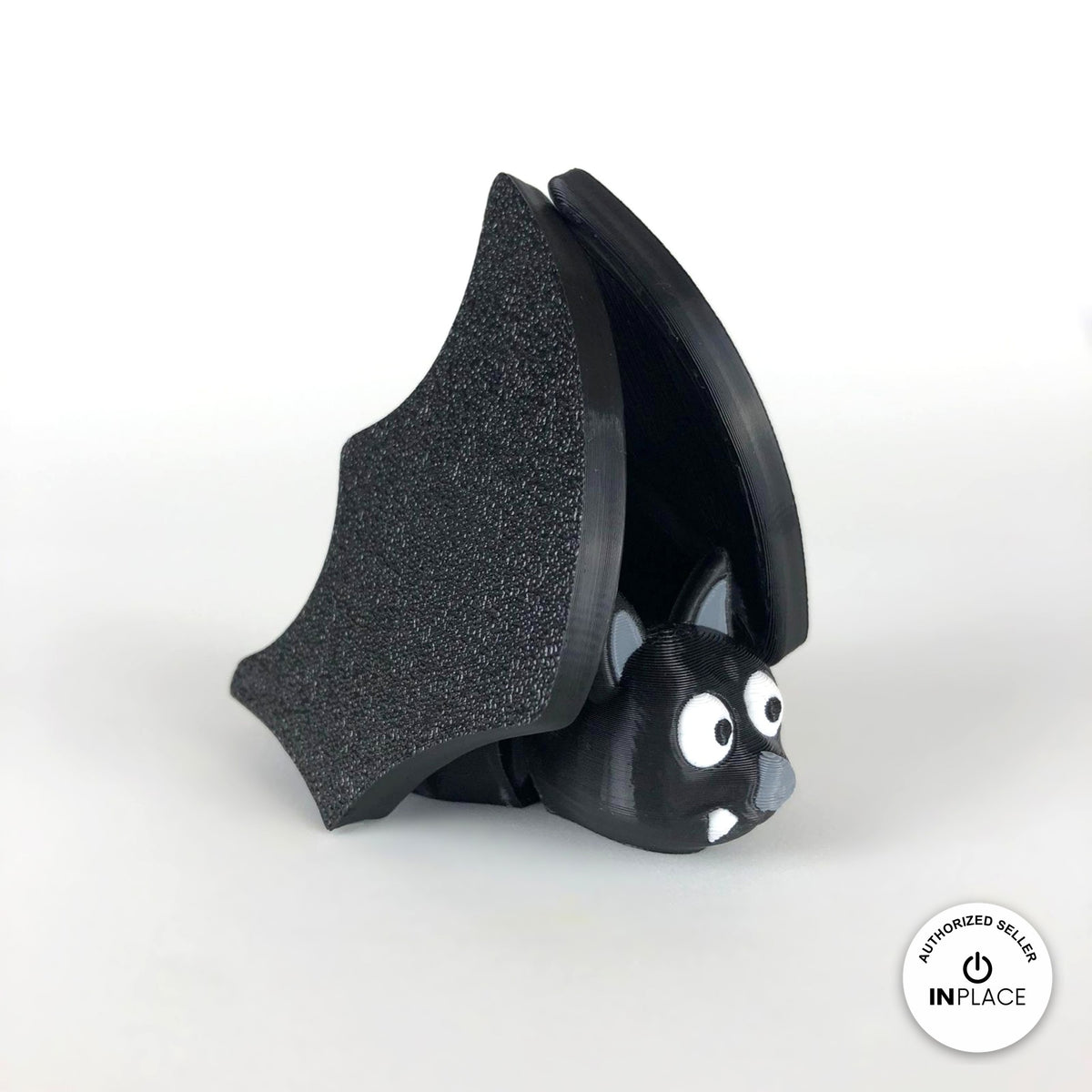 Cute bat keychain, 3D printed by RU3D – wings folded close up. Black with grey ears and white fangs.