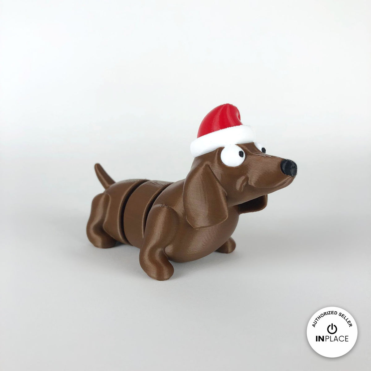 Cute Christmas dachshund keychain, 3D printed by RU3D – three quarter view facing right. Brown sausage dog with red Santa hat.