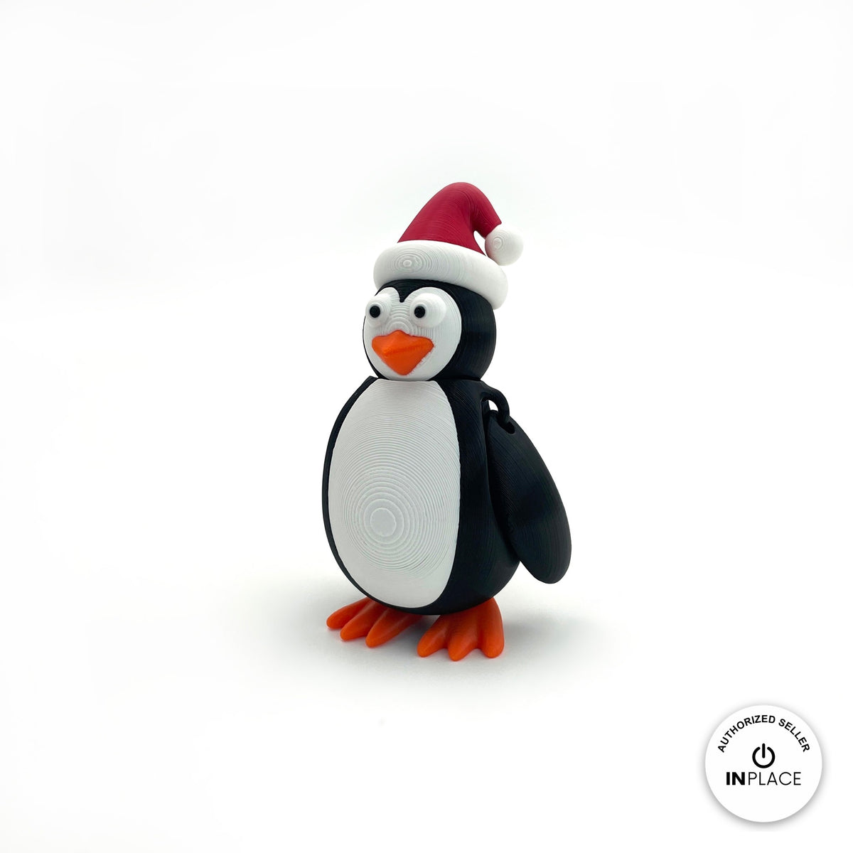 Cute Christmas penguin keychain, 3D printed by RU3D – three quarter view facing left. Black and white with red Santa hat and orange feet.
