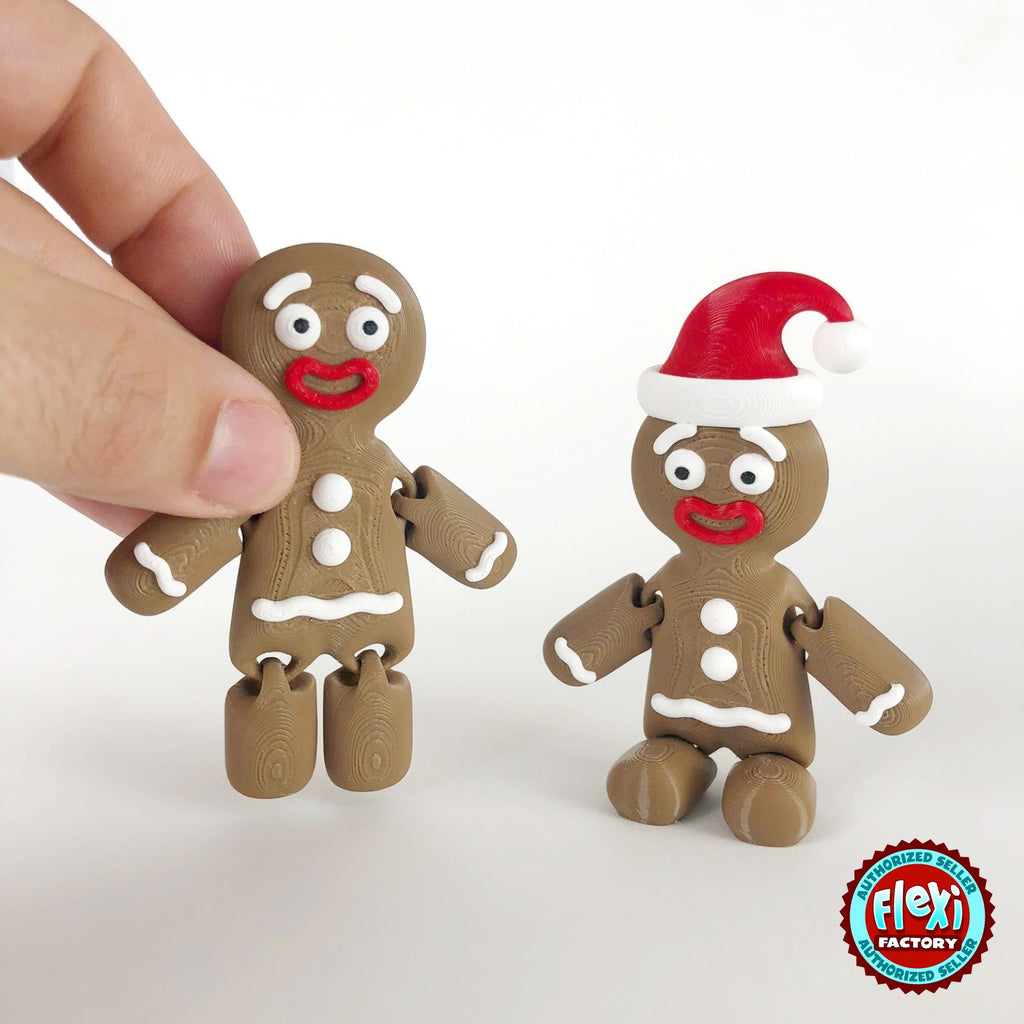 Cute gingerbread man keychain, 3D printed by RU3D – held in hand next to Santa hat version. Brown with white icing and red Santa hat.