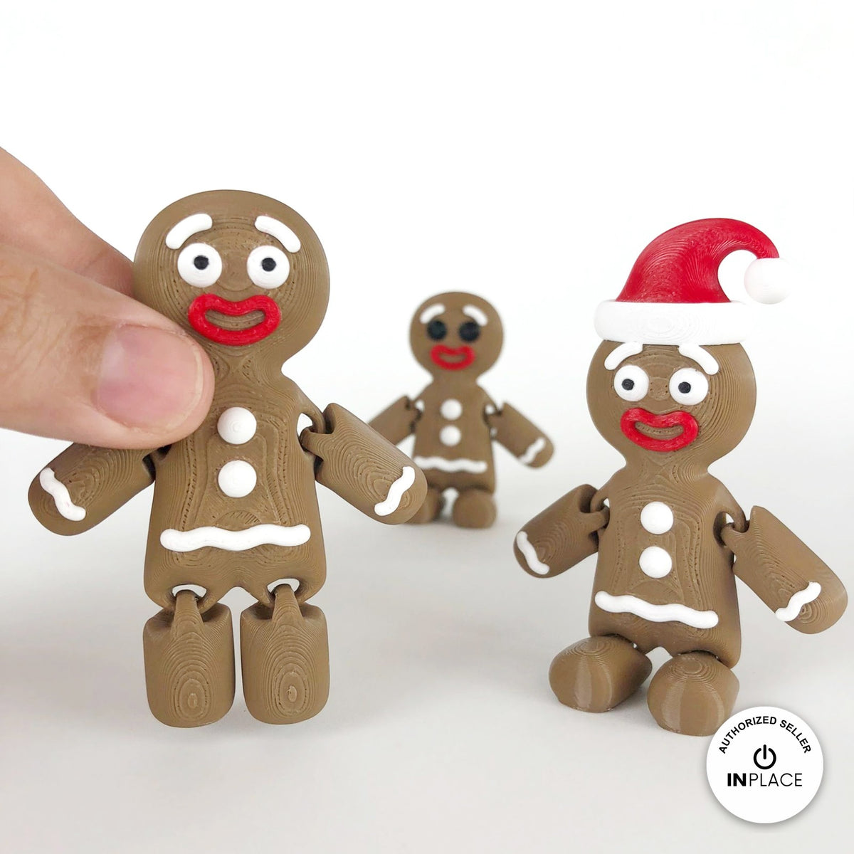 Cute gingerbread man keychain, 3D printed by RU3D – held in hand with friends. Brown with white icing and red Santa hat.