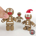 Cute gingerbread man keychain, 3D printed by RU3D – held in hand with friends. Brown with white icing and red Santa hat.