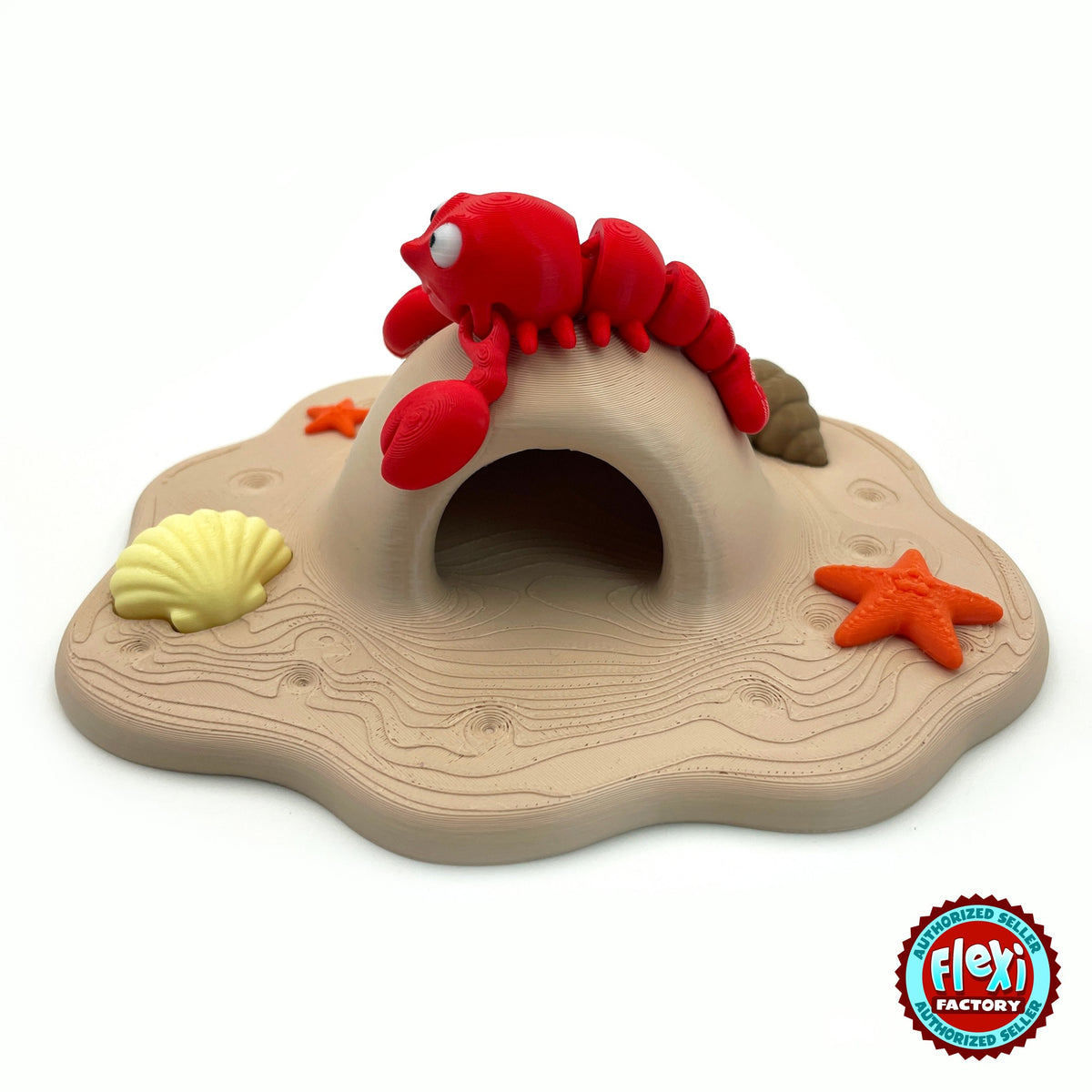 Cute lobster keychain, 3D printed by RU3D – on top of beach cave playset. Bright red with sandy beach cave playset.