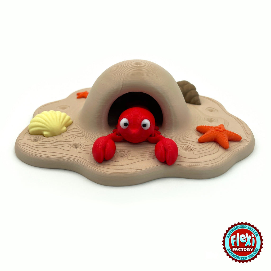 Cute lobster keychain, 3D printed by RU3D – peeking out of beach cave playset. Bright red with sandy beach cave playset.