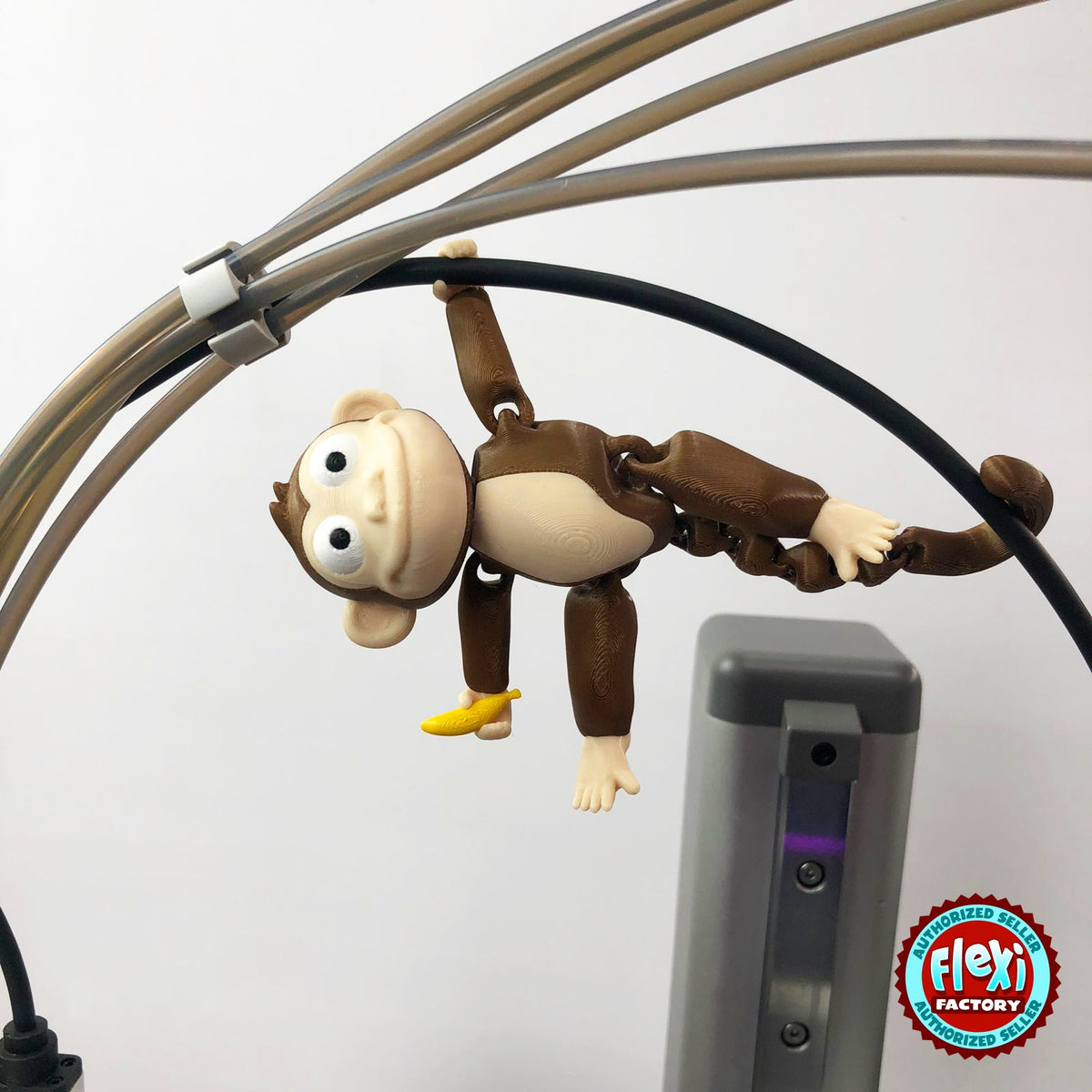 Cute monkey keychain, 3D printed by RU3D – hanging by arm and tail. Brown with cream face and yellow banana.