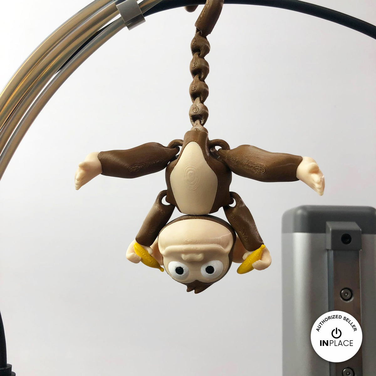 Cute monkey keychain, 3D printed by RU3D – hanging upside down. Brown with cream face and yellow banana.