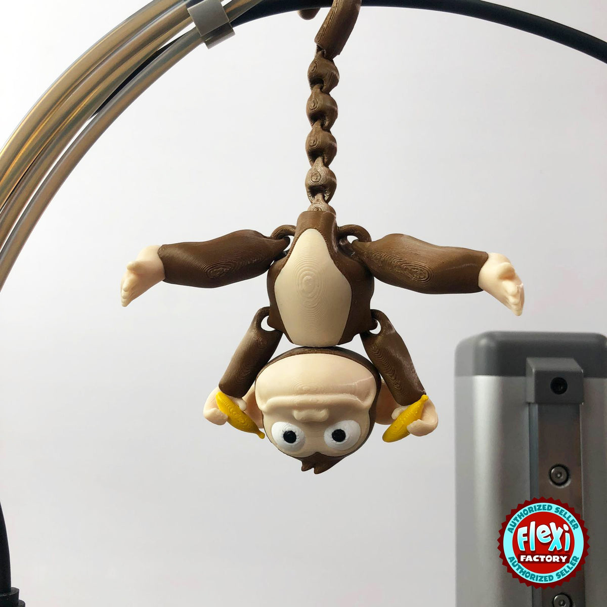 Cute monkey keychain, 3D printed by RU3D – hanging upside down. Brown with cream face and yellow banana.