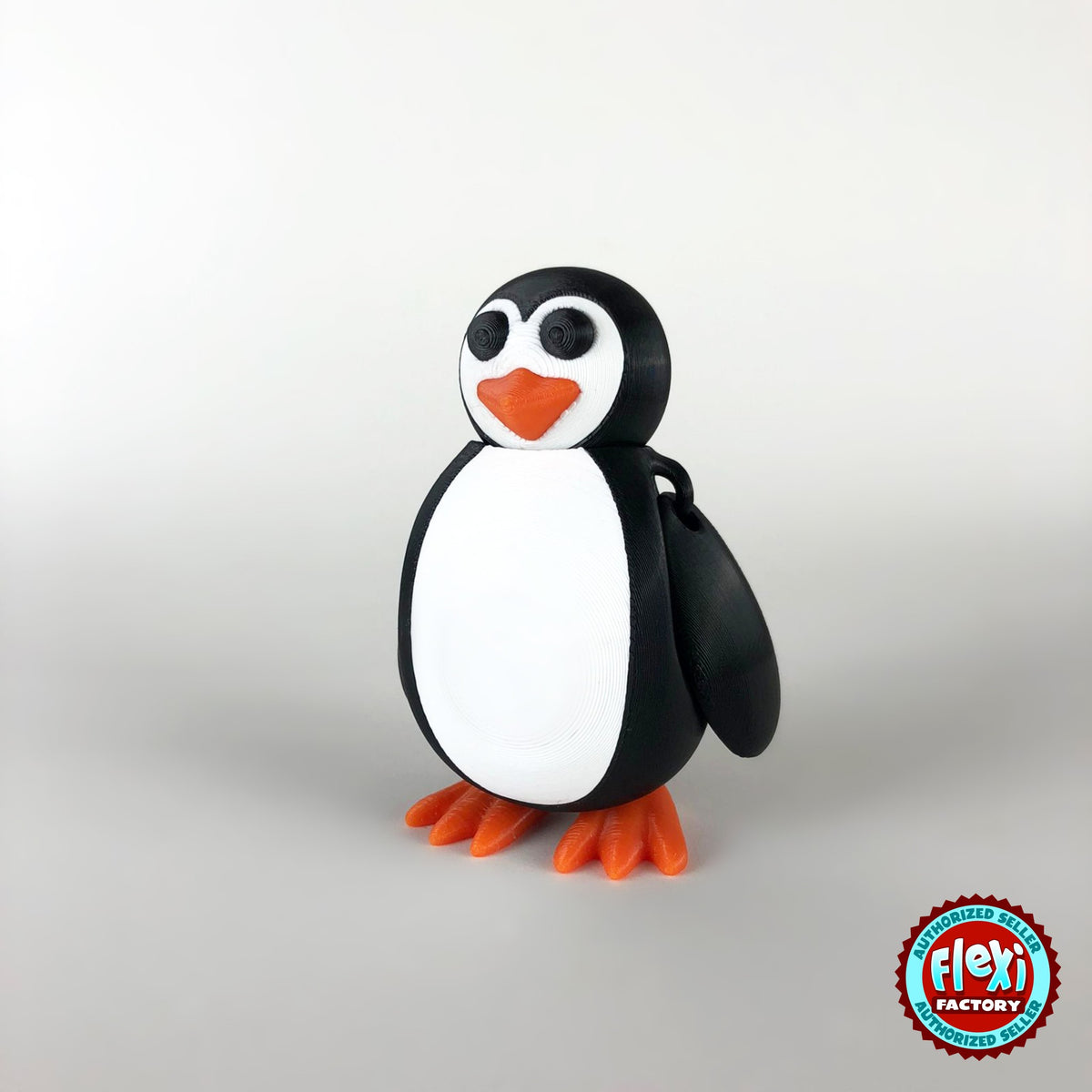 Cute penguin keychain, 3D printed by RU3D – dark eyes three quarter view facing right. Black and white with orange beak and feet.