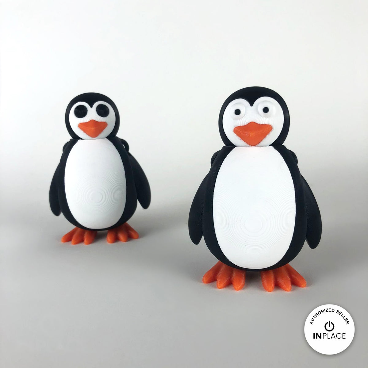 Cute penguin keychain, 3D printed by RU3D – pair of penguins. Black and white with orange beak and feet.