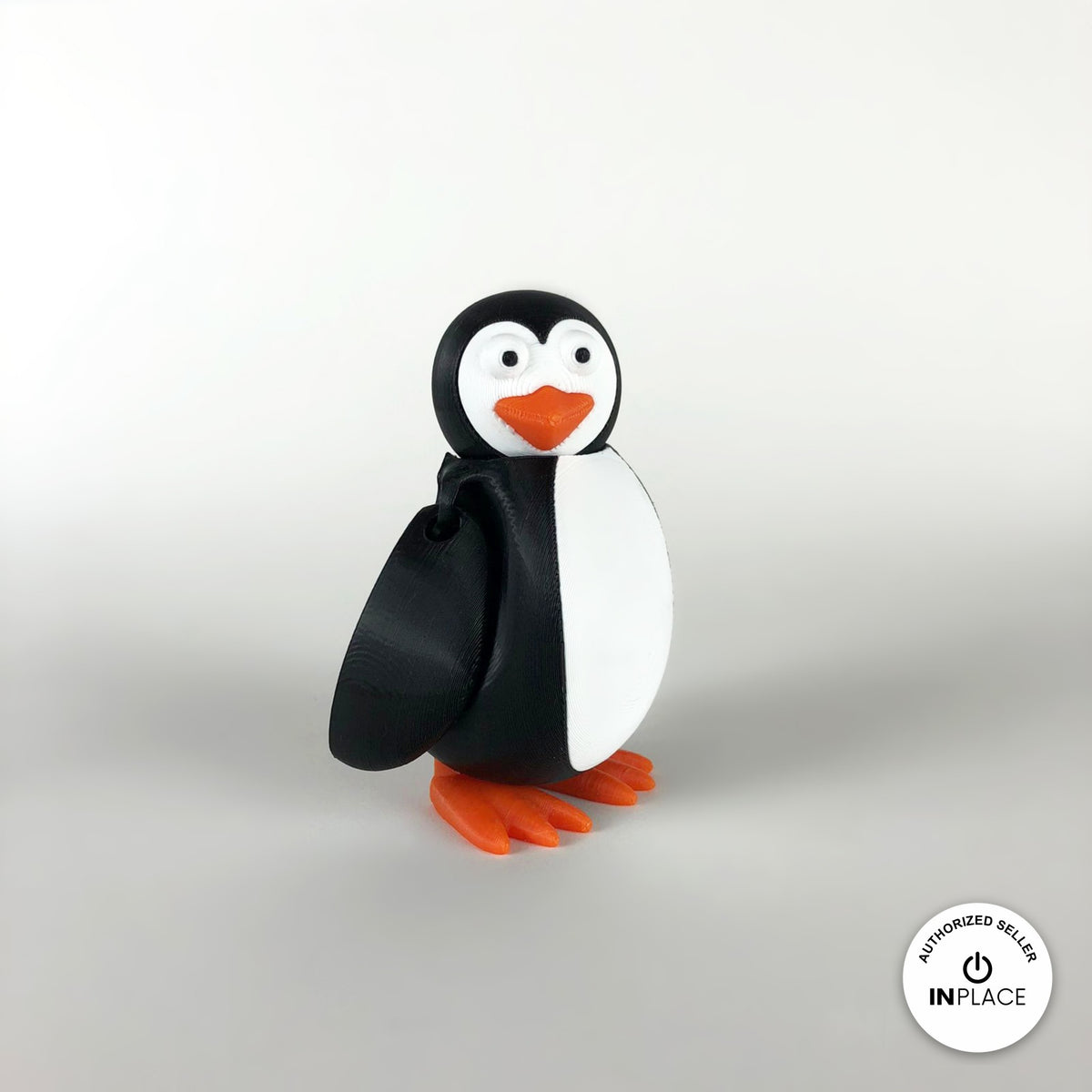 Cute penguin keychain, 3D printed by RU3D – side view facing left. Black and white with orange beak and feet.