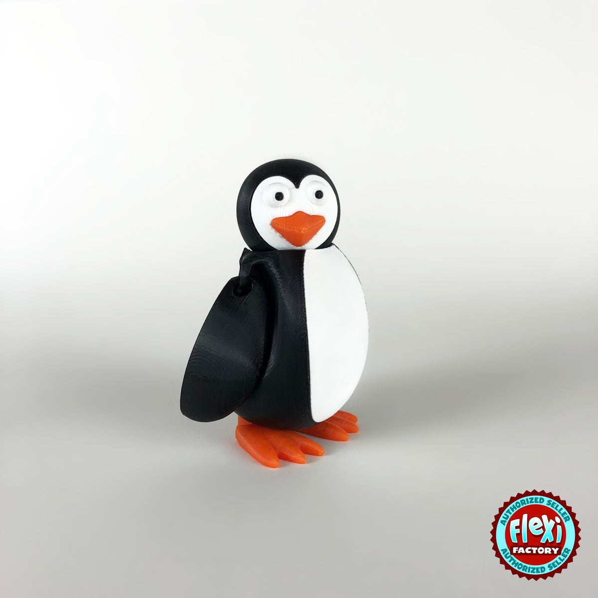 Cute penguin keychain, 3D printed by RU3D – side view facing left. Black and white with orange beak and feet.