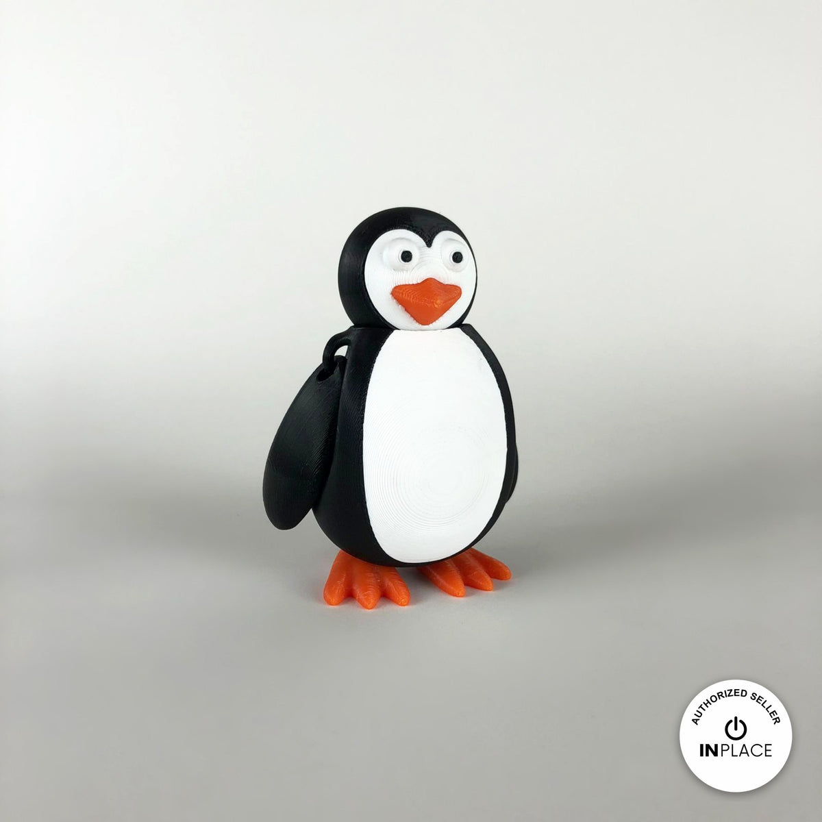 Cute penguin keychain, 3D printed by RU3D – three quarter view facing left. Black and white with orange beak and feet.