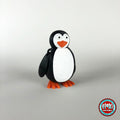 Cute penguin keychain, 3D printed by RU3D – three quarter view facing left. Black and white with orange beak and feet.