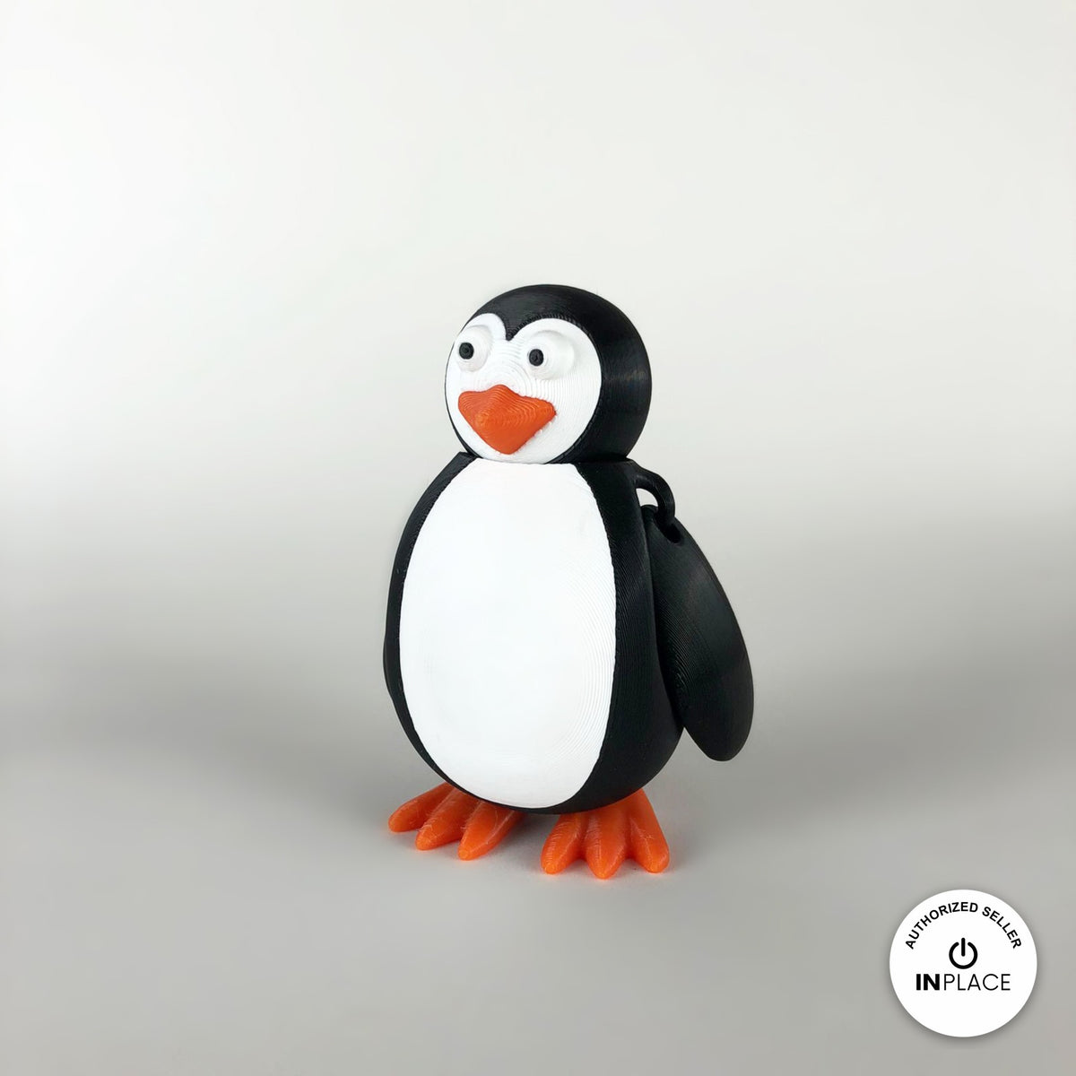 Cute penguin keychain, 3D printed by RU3D – three quarter view facing right. Black and white with orange beak and feet.