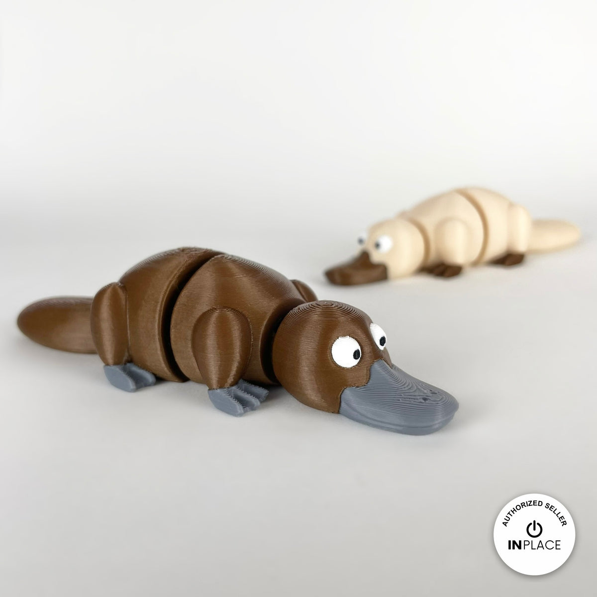 Cute platypus keychain, 3D printed by RU3D – brown platypus with cream behind. Brown with grey bill, also in cream.