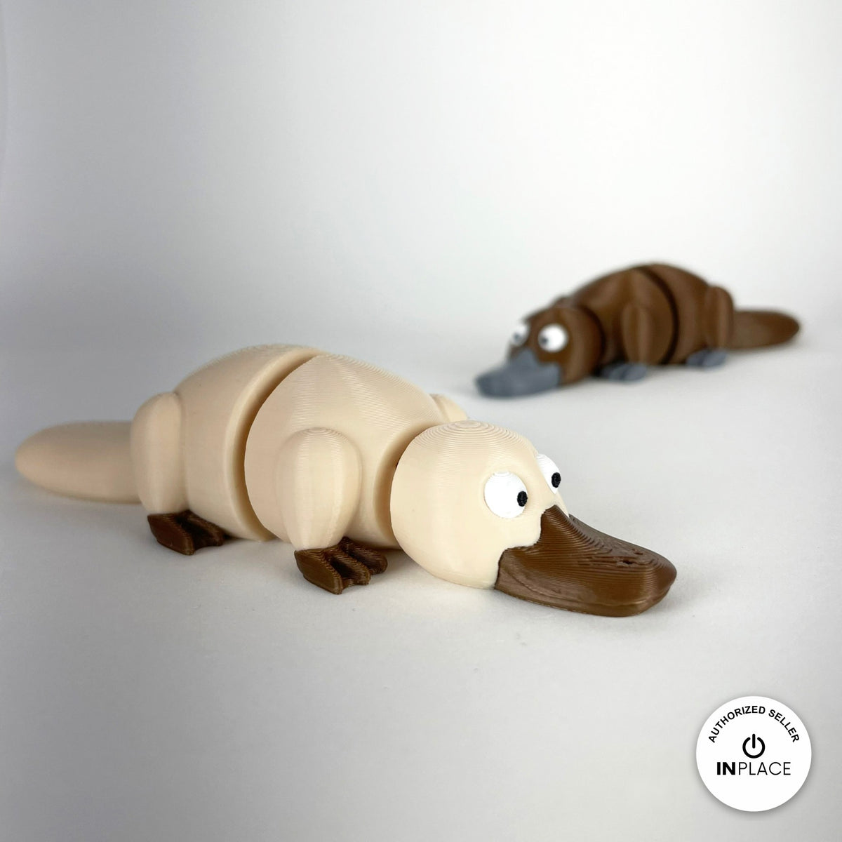 Cute platypus keychain, 3D printed by RU3D – cream platypus with brown behind. Brown with grey bill, also in cream.