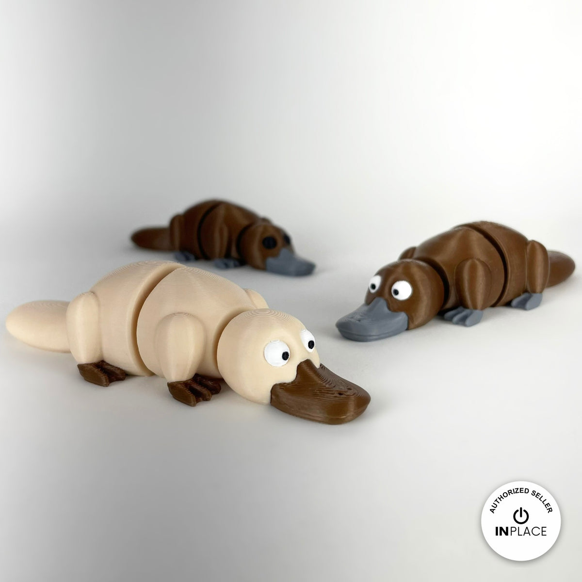 Cute platypus keychain, 3D printed by RU3D – group of platypuses cream in front. Brown with grey bill, also in cream.