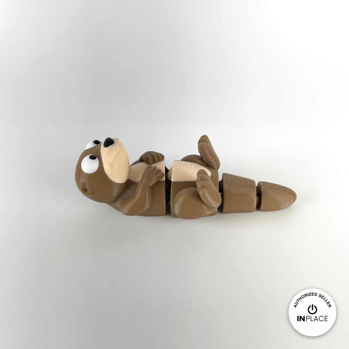 Cute river otter keychain, 3D printed by RU3D – lying on back facing left. Brown with cream belly.