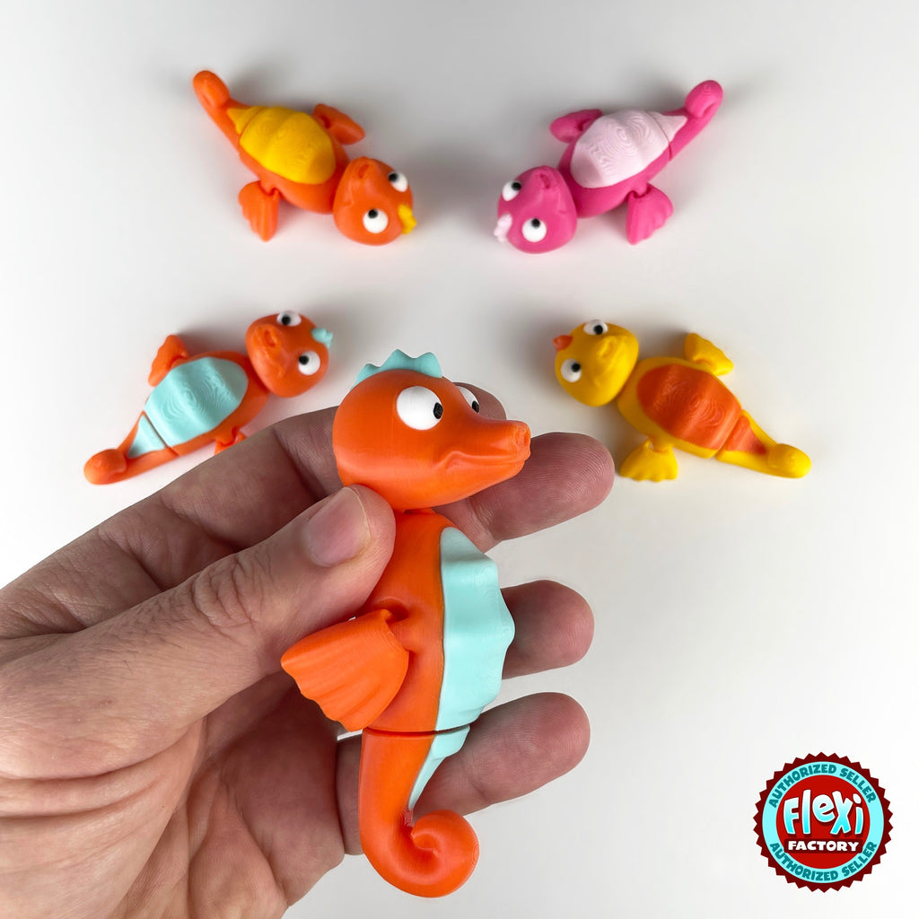 Cute seahorse keychain, 3D printed by RU3D – held in hand with friends. Orange with mint belly, also pink and yellow.