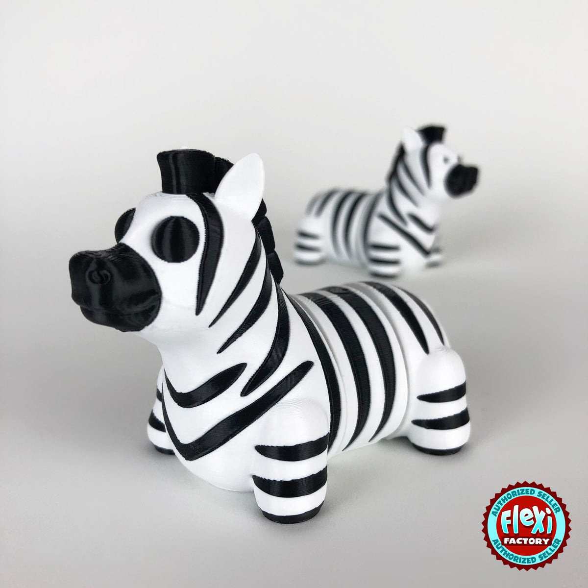 Cute zebra keychain, 3D printed by RU3D – close up with zebra behind. Black and white stripes.