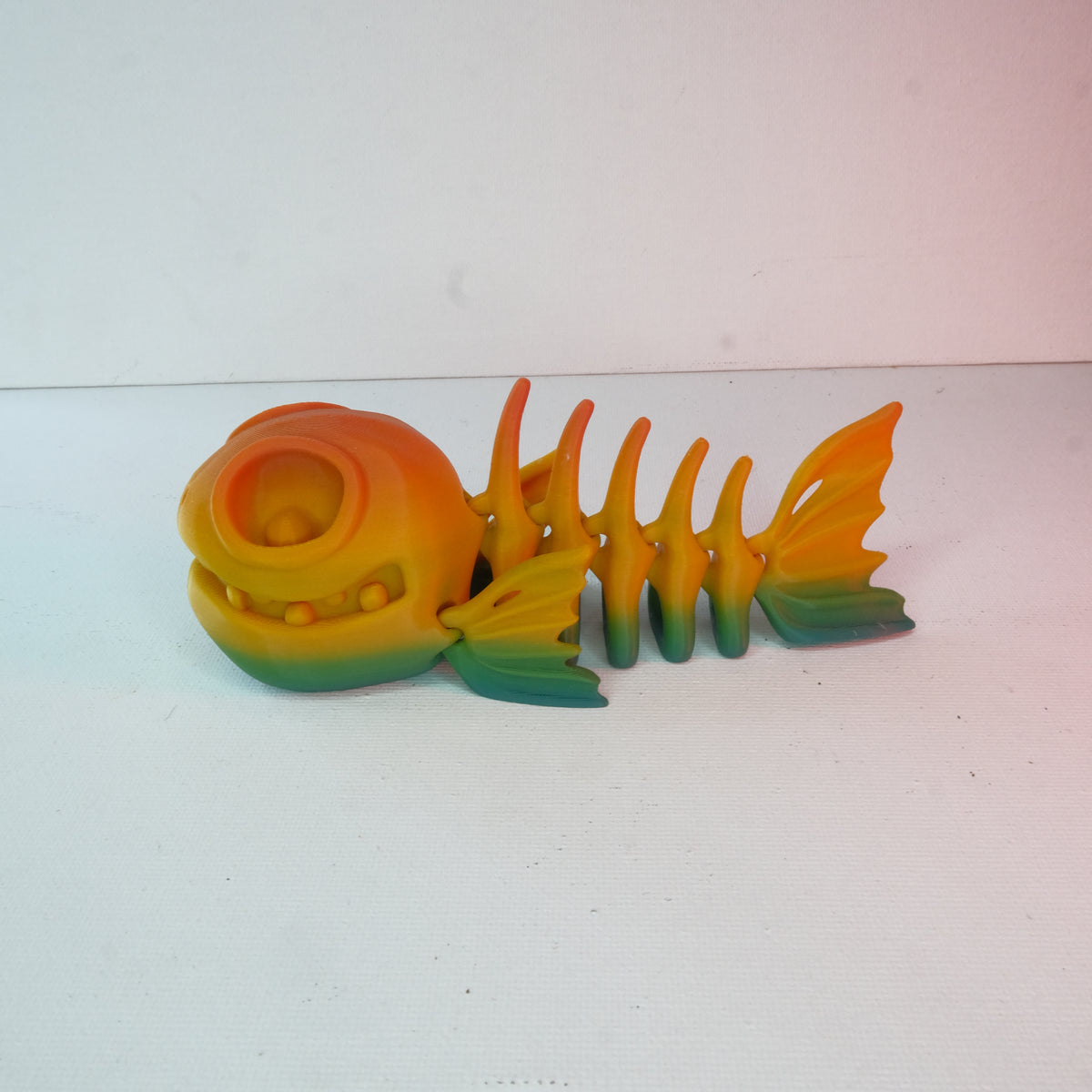 A novelty fish-shaped figurine with a smooth surface, featuring a gradient of colors from yellow to green and orange.