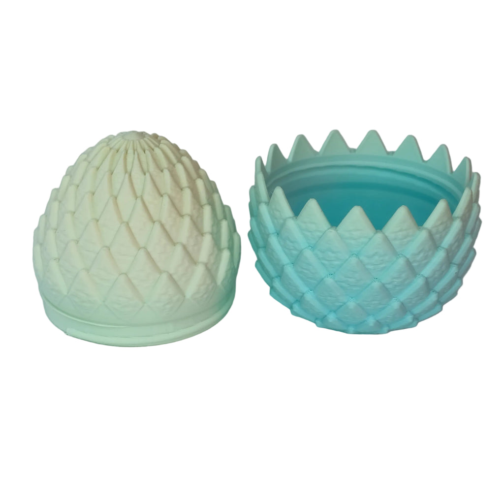 Two ornate boxes with interlocking lids, one in a smooth blue color and the other in a light pastel color, each resembling a sculpted design.