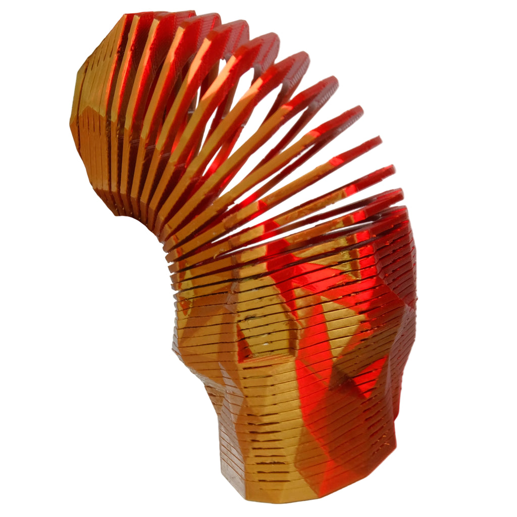 A spiral-patterned geometric figurine in orange that reflects light, held by a hand.